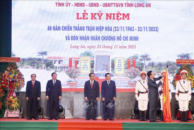 Chủ tịch nước Võ Văn Thưởng gắn Huân chương Hồ Chí Minh lên cờ truyền thống của tỉnh Long An - Ảnh: TTXVN